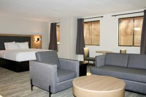 a hotel room with a bed and a couch and chairs at The Cairn Hotel in Cedar City +31 photos