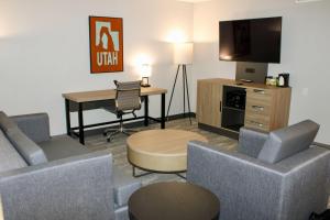 a hotel room with a desk and a tv and chairs at The Cairn Hotel in Cedar City