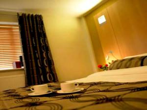レア・グリーンにあるThe Motel, Ribby Hall Villageのベッドルーム1室(テーブルにカップ2つが付いたベッド1台付)