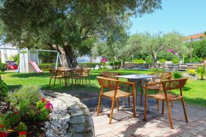 a group of tables and chairs under a tree at Nikiforos Village in Hanioti
