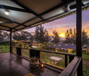 a balcony with a view of a sunset at Cozzy Villa Hajeka in Palayangan