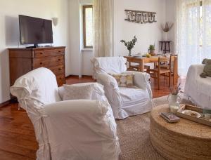 a living room with white furniture and a tv at ECO - Villa Giulia in Dormelletto
