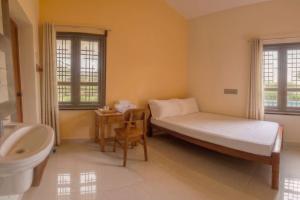 a bedroom with a bed and a sink and a toilet at The Sparrow in Kanyakumari