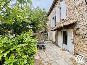 a stone house with a bench in front of a building at La prade in Saint-Ferriol