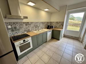 a kitchen with green cabinets and a sink and a window at La prade in Saint-Ferriol