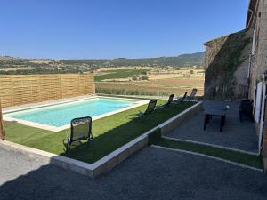 a swimming pool with chairs sitting next to a building at La prade in Saint-Ferriol