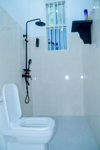 a white bathroom with a toilet and a window at Ray Infinity Suites in Paje