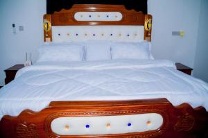 a large bed with a wooden headboard and white sheets at Ray Infinity Suites in Paje