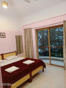 a bedroom with a bed and a large window at Nature Trinity House in Panchgani
