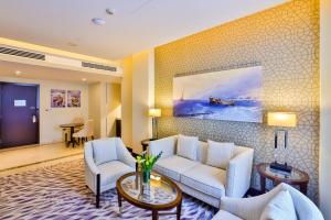 a living room with a couch and chairs and a painting at Riviera Rayhaan by Rotana Doha in Doha