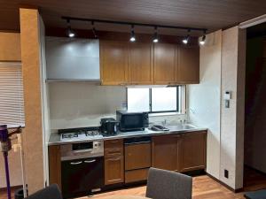 a kitchen with wooden cabinets and a stove and a sink at 伊勢神楽別邸 in Ise