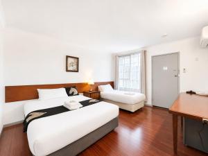 a bedroom with a large bed and a desk at Beaconsfield Lodge Motel in Beaconsfield