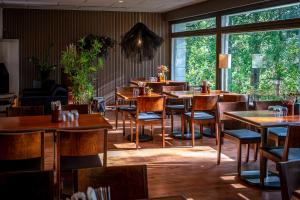 a restaurant with wooden tables and chairs and windows at Sveitsin Maja in Hyvinkää