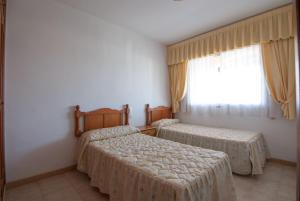 ガンディアにあるApartamentos Marblau Los Iris- Julio y Agosto SOLO FAMILIASのベッドルーム1室(ベッド2台、窓付)