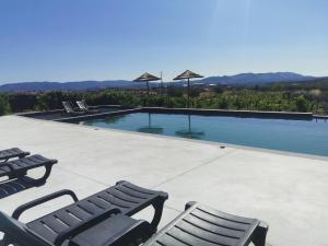 a swimming pool with two chairs and umbrellas at A Flor da Rosa in Vila Nova de Foz Coa