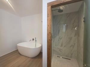 a bathroom with a white tub and a shower with a glass door at Triton Authentic Cretan Hotel in Tsoutsouros