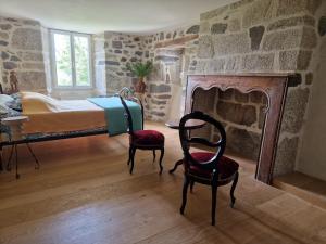 a bedroom with a bed and two chairs and a fireplace at Le Domaine Eugenie in Cassuéjouls