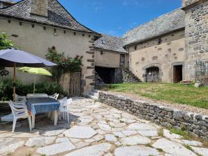 a table and chairs with an umbrella on a stone patio at Le Domaine Eugenie in Cassuéjouls