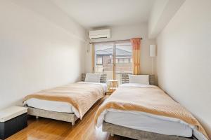 two beds in a room with a window at 大濠ウエストビレッジ209 in Fukuoka