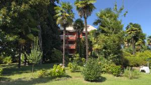 a resort building with palm trees in a yard at ECO - Villa Giulia in Dormelletto