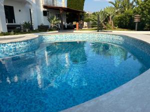 a swimming pool with blue water in front of a house at VILLA CLARA ISCHIA piscina riscaldata e idromassaggio in Lacco Ameno