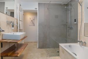 a bathroom with a shower and a sink and a tub at Gemütliches Ferienhaus in Kell am Traumpfad nahe Maria Laach in Andernach +7 photos
