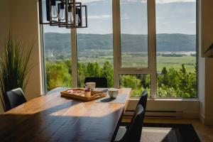 a dining room table with chairs and a large window at Elegant Condo - Balcony Pool & Stunning View in Baie-Saint-Paul