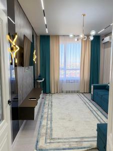 a living room with a blue couch and a large window at Улы Дала in Shymkent