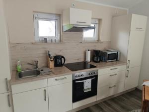 a kitchen with white cabinets and a sink and a microwave at NEU! Ferienhaus Schwedt in Schwedt