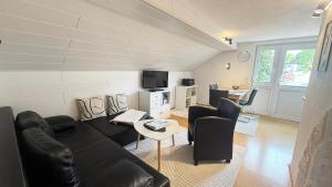 a living room with a black leather couch and chairs at Appartement Pension Schüßler in Waldeck