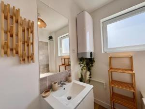 a white bathroom with a sink and a mirror at Le Cocon Doré in Calais