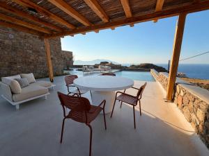 a patio with a table and chairs and the ocean at Lucevista Mykonos Villas in Fanari