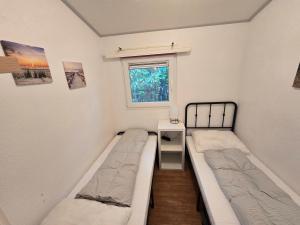 two beds in a small room with a window at Chalet Ankerplatz in Lauwersoog in Lauwersoog
