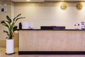 a reception desk with a potted plant and clocks at 씨뷰 호텔 in Naedo-dong