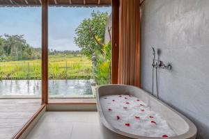 a bath tub sitting in a room with a window at Aranya Ubud Villa in Ubud