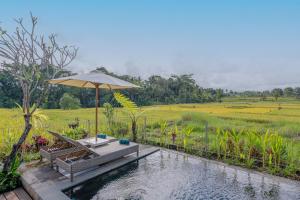 a pool with an umbrella next to a field at Aranya Ubud Villa in Ubud +102 photos