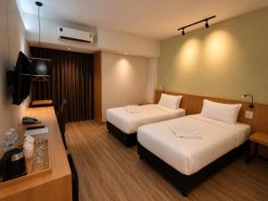a hotel room with two beds and a television at The Neuf@Ratchada in Bangkok