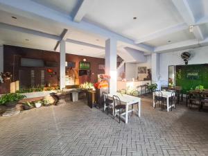 a restaurant with tables and chairs and a large screen at RedDoorz near Ramayana Mall Banyuwangi in Banyuwangi