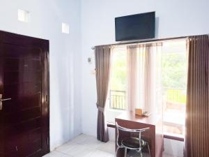 a room with a desk with a chair and a window at RedDoorz near Ramayana Mall Banyuwangi in Banyuwangi