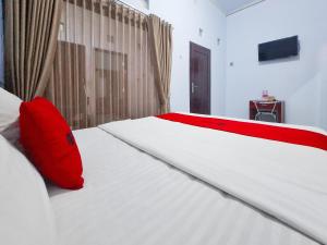 a bedroom with a bed with a red pillow on it at RedDoorz near Ramayana Mall Banyuwangi in Banyuwangi