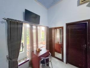 a room with a desk and a window with a television at RedDoorz near Ramayana Mall Banyuwangi in Banyuwangi +13 photos
