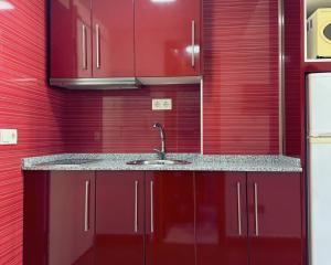 a kitchen with red cabinets and a sink at Brisa de Torre in Torre del Mar
