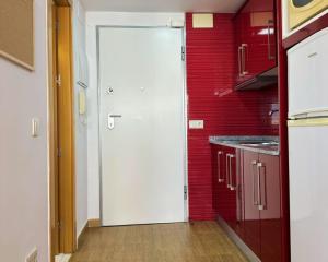 a kitchen with a white door and a red wall at Brisa de Torre in Torre del Mar