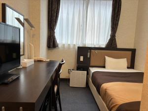 a hotel room with a bed and a desk with a television at Kyoto Central Inn in Kyoto