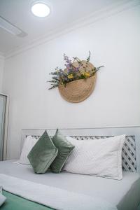 a basket of flowers on the wall above a bed at Mbuyu Taifa Greenview Mlandege Apartment in Zanzibar City