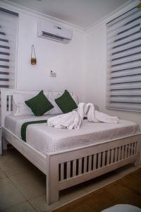 a white bed with towels on it in a bedroom at Mbuyu Taifa Greenview Mlandege Apartment in Zanzibar City