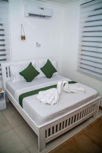 a white bed with towels on it in a room at Mbuyu Taifa Greenview Mlandege Apartment in Zanzibar City