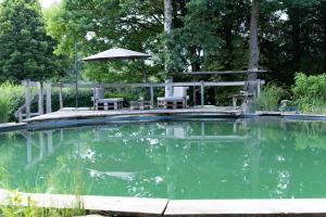 a swimming pool with two chairs and an umbrella at Ferienwohnung Donautal in Meßkirch