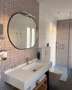 a bathroom with a sink and a mirror and a toilet at Hôtel Valencia in Hendaye