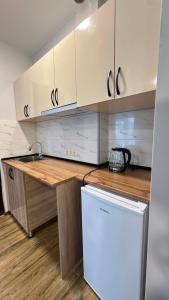 a kitchen with white cabinets and a white refrigerator at Hotel Nena in Kobuleti